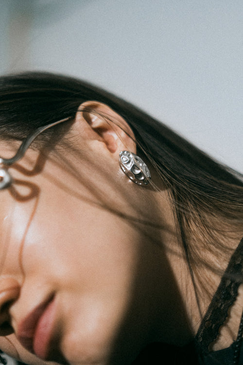 Boucles d’oreilles Relief en acier inoxydable argenté, portées, gros plan sur l’oreille