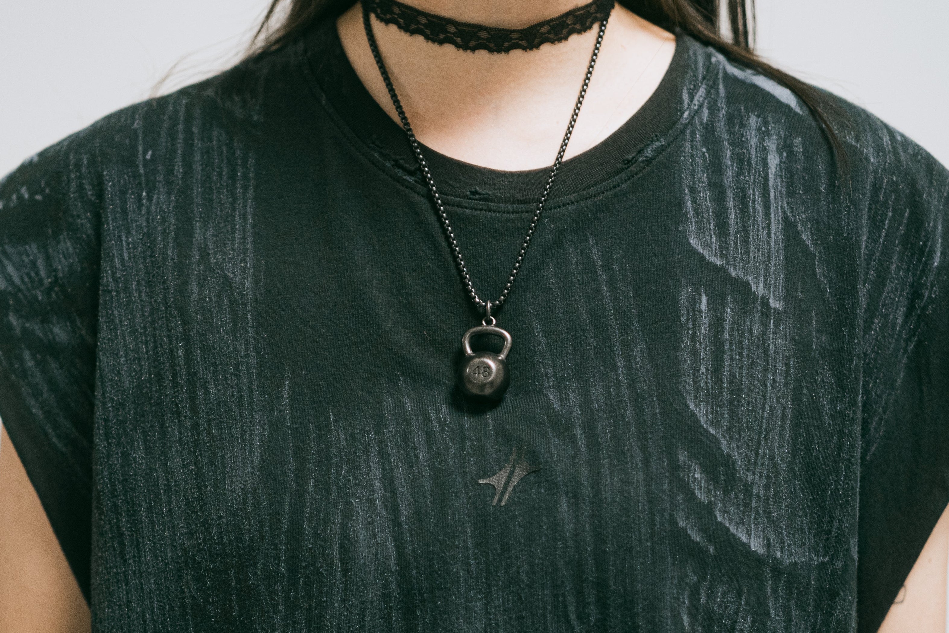 Pendentif Stabilizer en acier inoxydable noirci mat avec chaîne, porté au cou sur un t-shirt noir