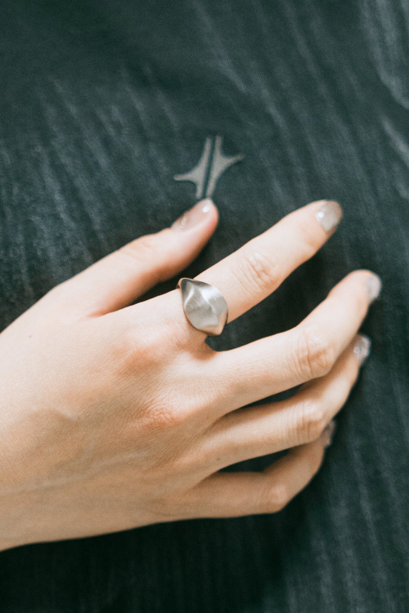 Bague Tabula en acier inoxydable argenté, portée à la main sur fond textile sombre