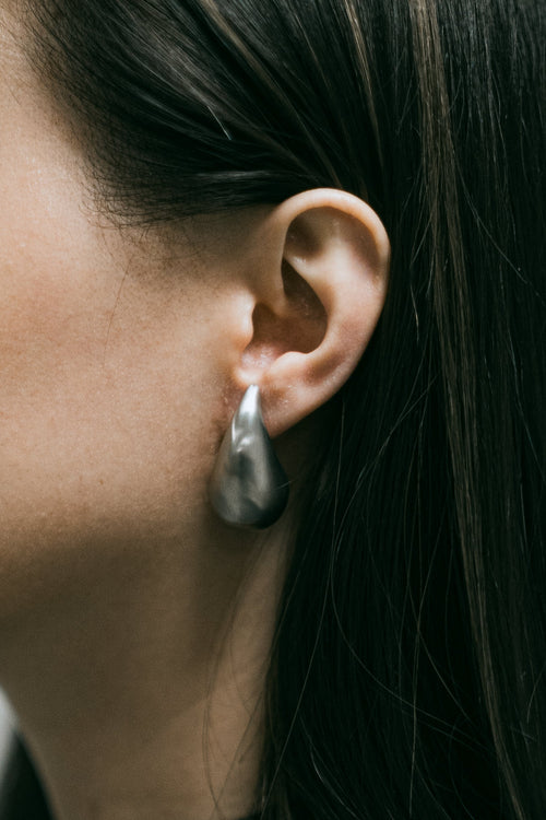Boucles d’oreilles Vector en acier inoxydable argenté, portées, gros plan sur l’oreille