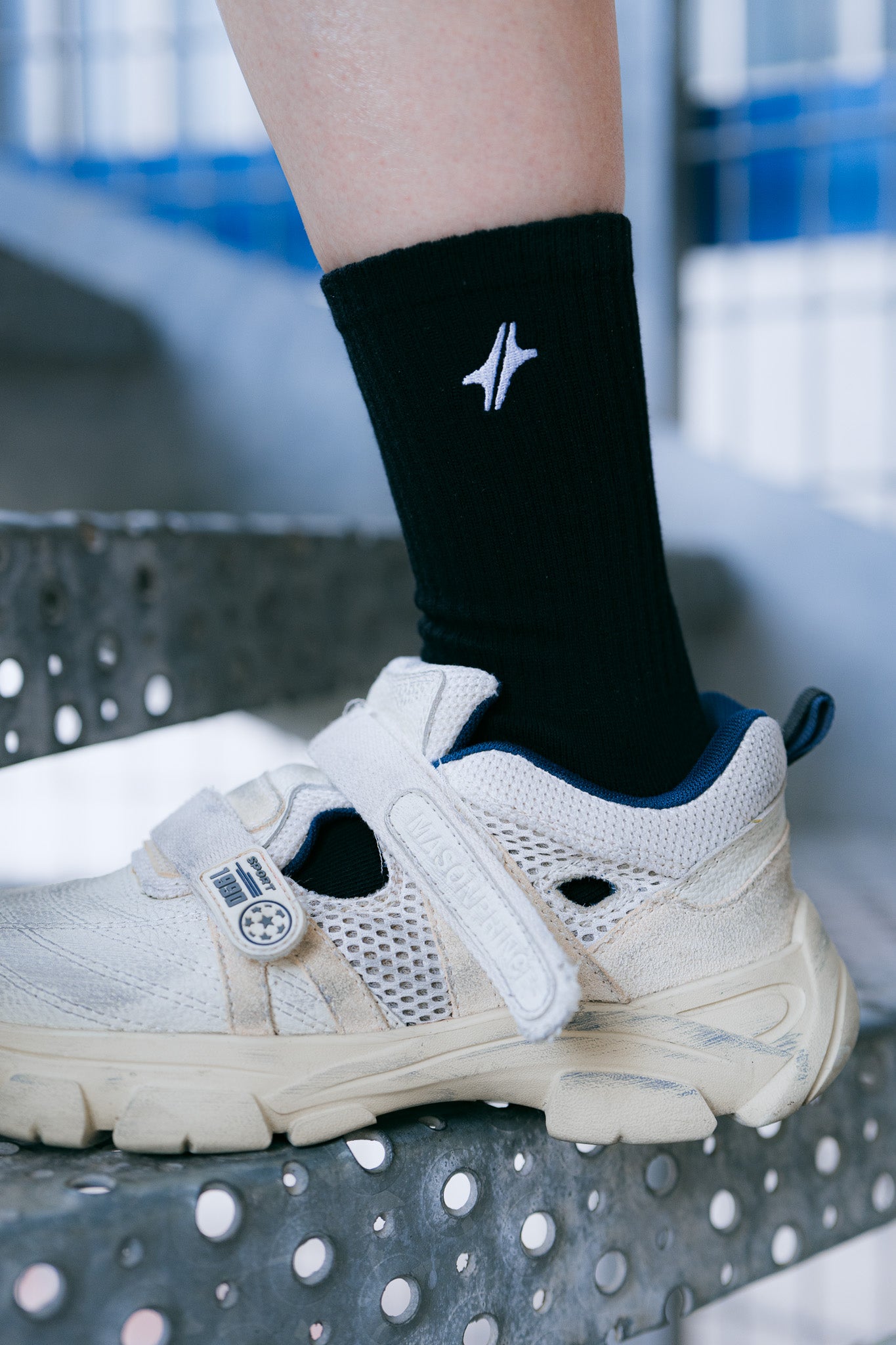 Chaussettes Strata en coton noir, gros plan sur le logo Module 48 brodé, portées avec une basket claire